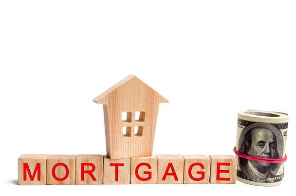 Wooden house and dollars with wooden blocks and the inscription mortgage. credit for property, apartment. Business loans for real estate. mortgage tax and insurance. white isolated background - Photo, image