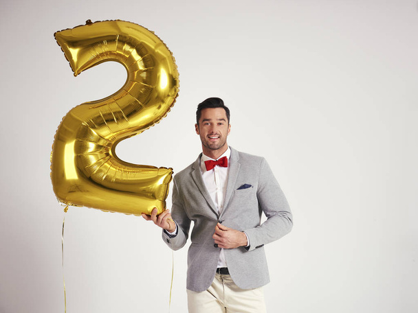 Jovem com balão dourado celebrando o segundo aniversário de sua empresa
 - Foto, Imagem