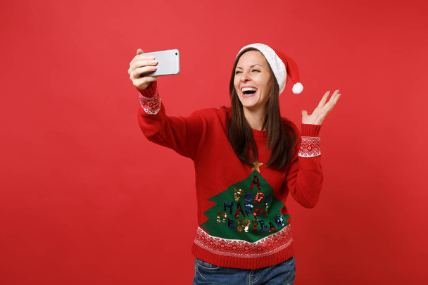Eller izole kırmızı zemin üzerine yayılan gülen Santa kız Noel şapka alarak selfie üstünde hareket eden telefon, atış yapıyor. Mutlu yeni yıl 2019 kutlama tatil parti kavramı. Kopyalama alanı alay - Fotoğraf, Görsel