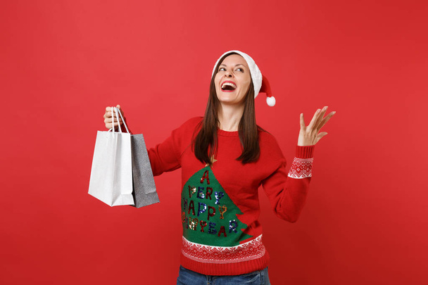 Happy Santa girl vzhlédl, šíření ruce, drží balíčky tašky s nákupy po nakupování izolované na červeném pozadí. Šťastný nový rok 2019 oslavu dovolenou stranou koncept. Vysmívat se kopie prostor - Fotografie, Obrázek
