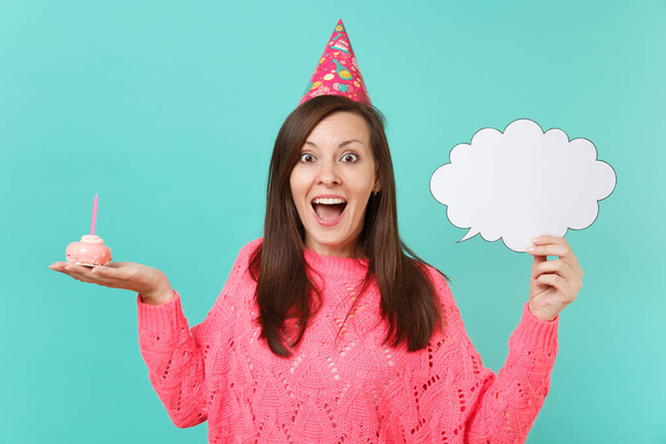 Excited young woman in birthday hat hold in hand cake with candle empty blank Say cloud speech bubble for promotional content isolated on blue background. People lifestyle concept. Mock up copy space - Photo, Image