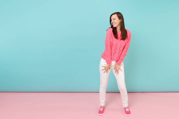 Retrato de comprimento total da jovem sorridente em camisola rosa de malha, calças brancas posando isoladas no fundo da parede azul pastel rosa brilhante em estúdio. Conceito de estilo de vida moda. Mock up espaço de cópia
 - Foto, Imagem