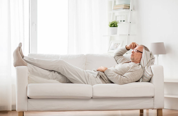 senior man  lying on sofa and thinking at home - Photo, image
