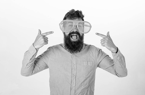Cheerful mood concept. Hipster looking through of giant striped sunglasses.Man with beard and mustache on happy face wears funny big eyeglasses, white background. Guy with beard pointing at himself - Фото, изображение