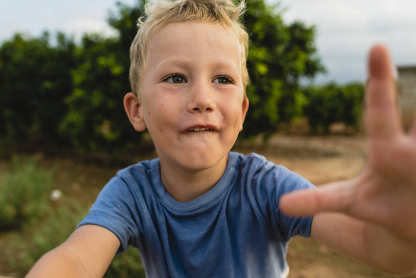 blonder Junge macht lustige Gesichter im Freien - Foto, Bild