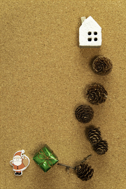 Marco de cono de pino con casa blanca y caja de regalo verde con Santa Claus
 - Foto, Imagen