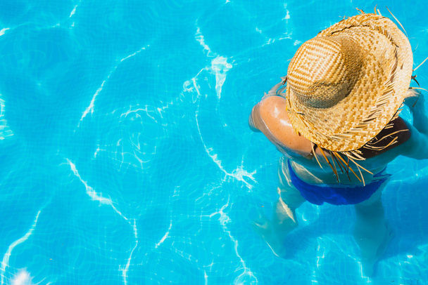 Женщина в бассейне со шляпой расслабленной и отдохнувшей
. - Фото, изображение
