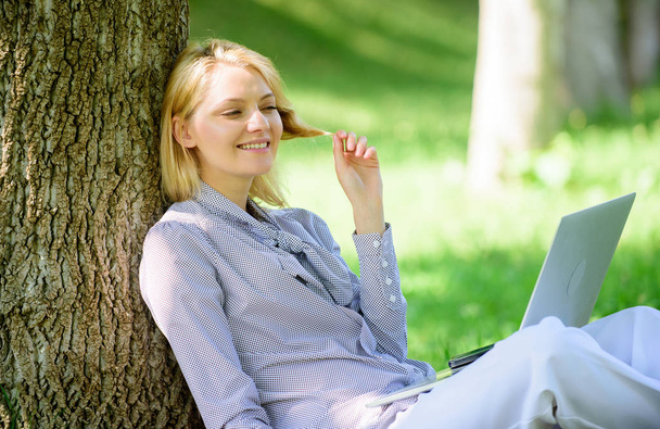 Girl work with laptop in park sit on grass. Education technology and internet concept. Natural environment office. Work outdoors benefits. Woman with laptop work outdoors lean tree. Minute for relax - Foto, Bild