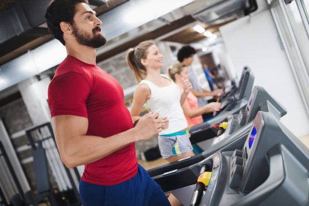 Young handsome man doing cardio training on treadmill in gym - Фото, зображення
