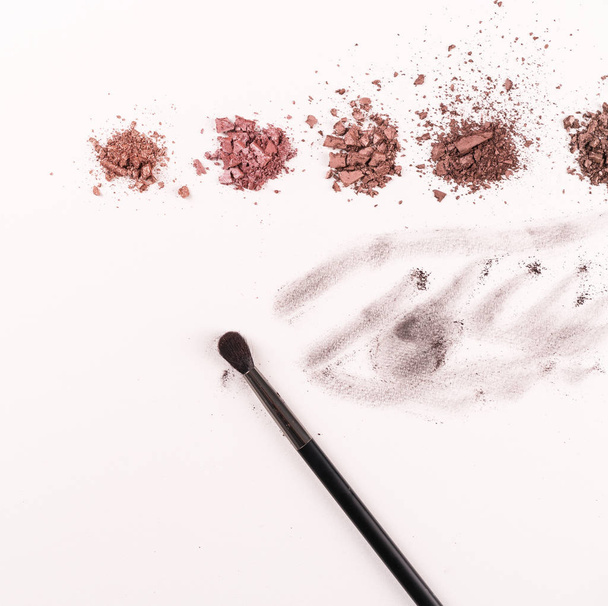 eye shadows in a line on a light paper backdrop, make up brush, eye drawn with these eye shadows - 写真・画像