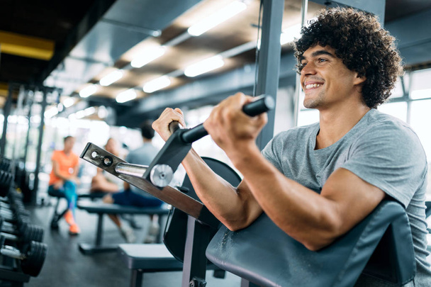 Man working out in gym on fitness machine - Photo, Image