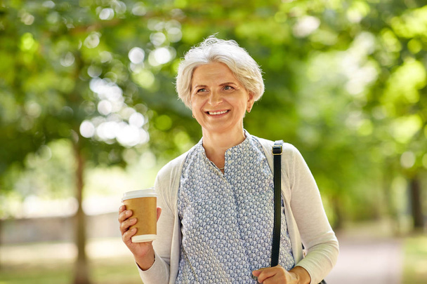 senior woman drinking takeaway coffee at park - Zdjęcie, obraz