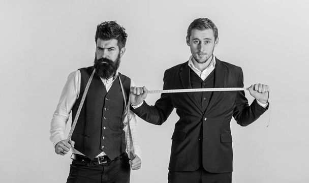 Portrait of two handsome young tailors posing with measuring tapes - Foto, Imagen