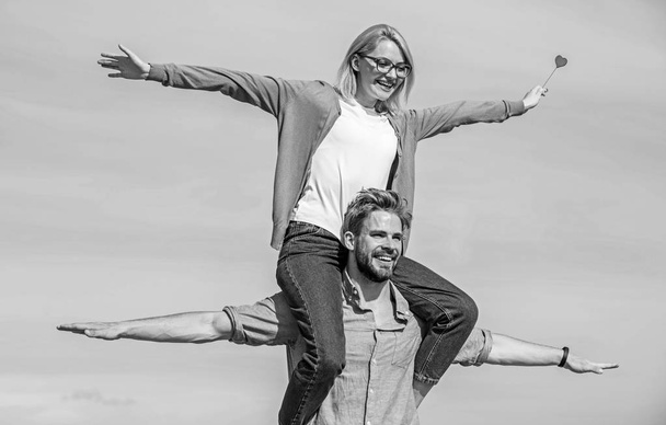 Freedom concept. Couple in love enjoy feeling freedom outdoor sunny day. Couple happy date having fun together. Man carries girlfriend on shoulders, sky background. Lovers enjoy date and feeling free - Foto, Bild