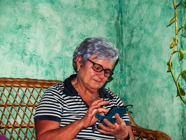 Une femme âgée écrit et envoie un message par téléphone avec un smartphone
 - Photo, image