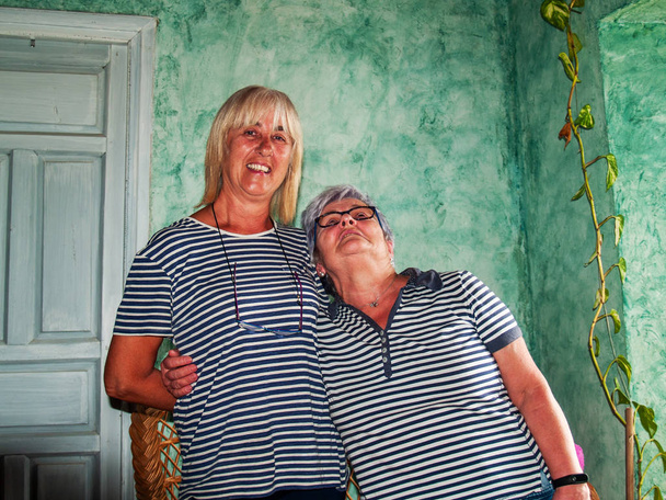 Kaksi naista sisaret halaavat hymyillen ja osoittaen onnea
 - Valokuva, kuva
