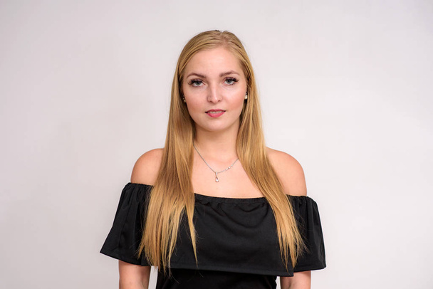 portrait of a beautiful blonde girl in a dress on a white background. She stands right in front of the camera in different poses and shows different emotions - Photo, image