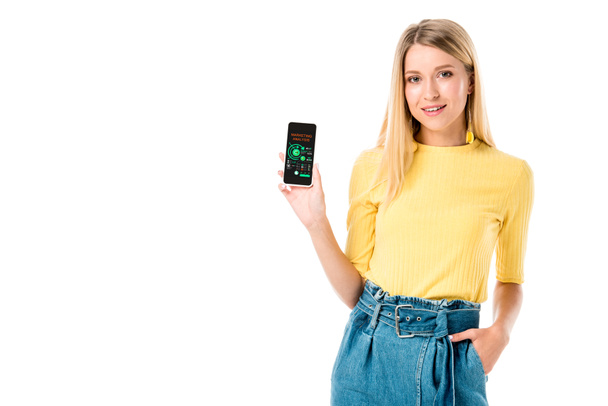 atraktivní mladá žena držící smartphone s marketingové analýzy aplikace a usmívá se na kameru izolované na bílém - Fotografie, Obrázek