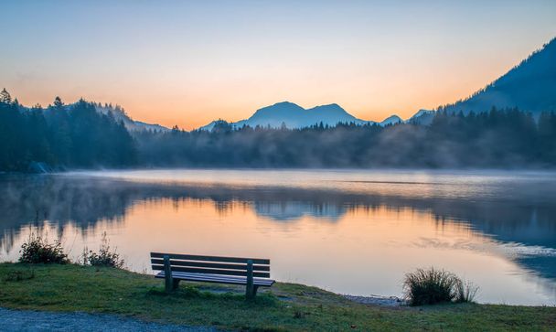 Plaats op de oever van Hintersee meer ontspannen bij zonsopgang. De mist verspreidt zich over het water. Magische schilderkunstige scène in Berchtesgaden Alpen, Duitsland - Foto, afbeelding