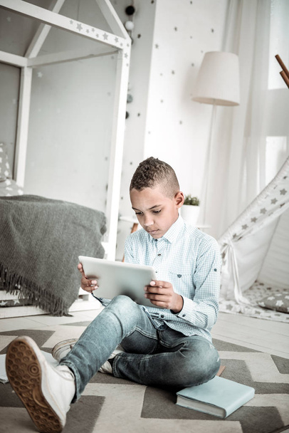 Smart cute boy sitting on the floor with a tablet - 写真・画像