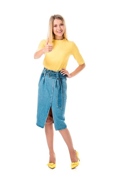 full length view of attractive girl showing thumb up and smiling at camera isolated on white  - Valokuva, kuva