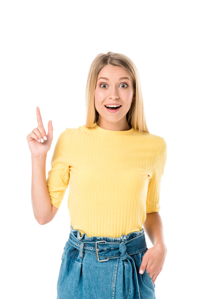 surprised young woman pointing up with finger and smiling at camera isolated on white - Photo, image