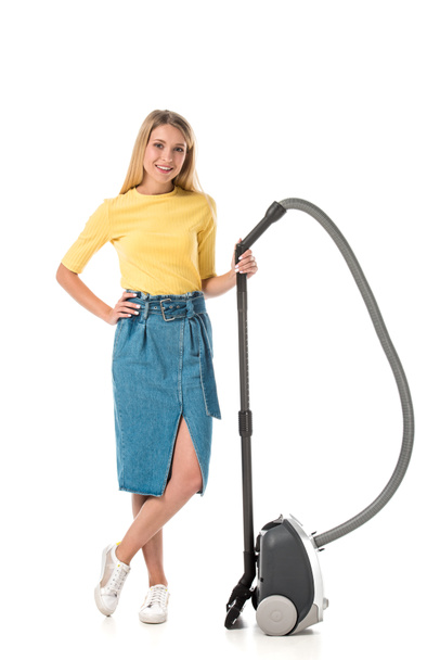 attractive young woman standing with vacuum cleaner and smiling at camera isolated on white  - Foto, immagini