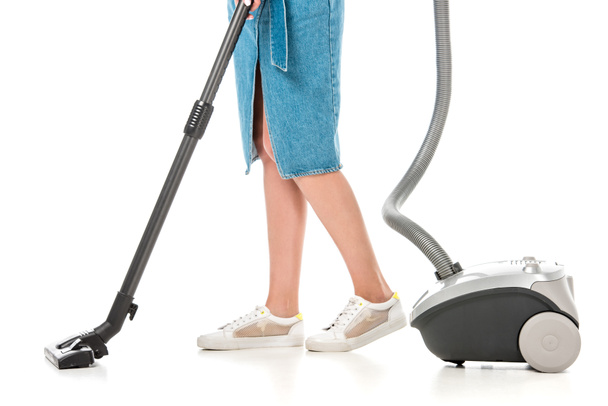 low section of young woman using vacuum cleaner isolated on white - 写真・画像