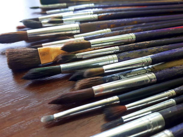 Old brushes are on the table, a palette of colors - Photo, Image