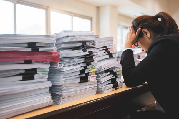 Trabajadora de oficina está angustiada con un montón de papeleo en su escritorio
 - Foto, imagen