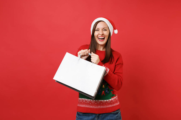Stunning merry young Santa girl holding packages bags with purchases after shopping isolated on bright red wall background. Happy New Year 2019 celebration holiday party concept. Mock up copy space - Foto, Imagem