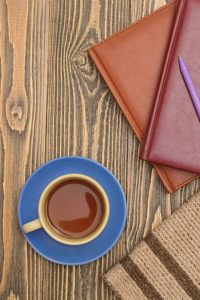 Modrý šálek s notebooky, tužku a šátek na dřevěný stůl. Svisle. - Fotografie, Obrázek