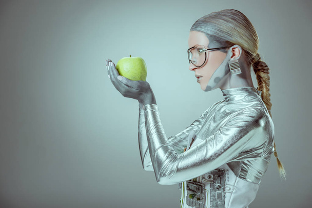 vista lateral del robot mujer sosteniendo manzana verde aislado en gris, concepto de tecnología futura
 - Foto, imagen