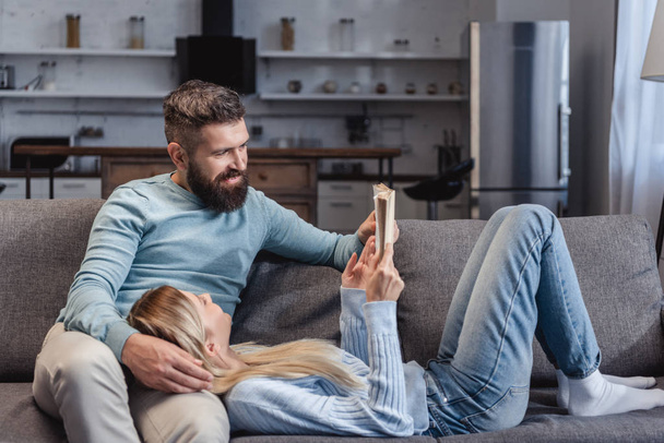 Wife holding book and lying on knees of husband - Photo, Image