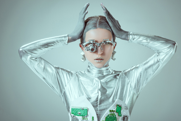 young woman robot touching head and looking at camera isolated on grey, future technology concept  - Photo, image