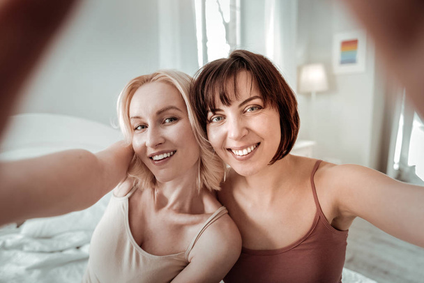 Contrast blond and brunet ladies making selfie - Фото, изображение