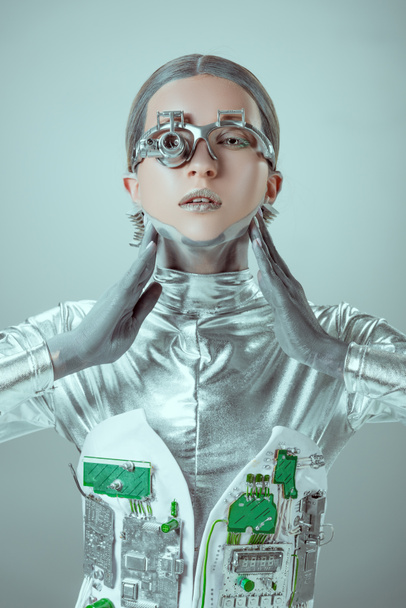 cyborg tocando pescoço e olhando para câmera isolada em cinza, conceito de tecnologia futuro
  - Foto, Imagem