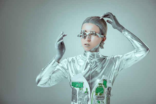 young woman robot touching head and looking away isolated on grey, future technology concept  - 写真・画像