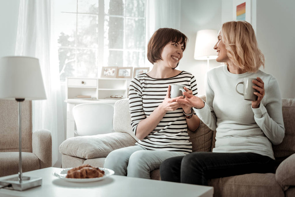 Mujeres alegres radiantes teniendo conversación expresiva durante el desayuno
 - Foto, imagen