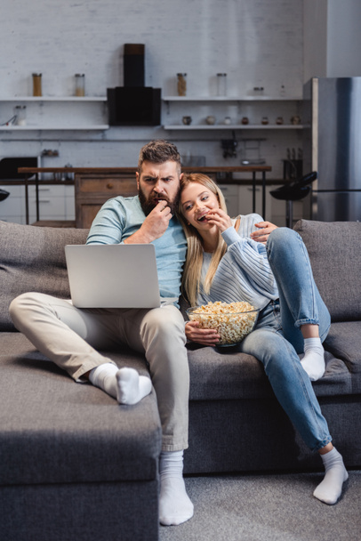 Husband and wife sitting on sofa and watching movie on laptop  - Valokuva, kuva