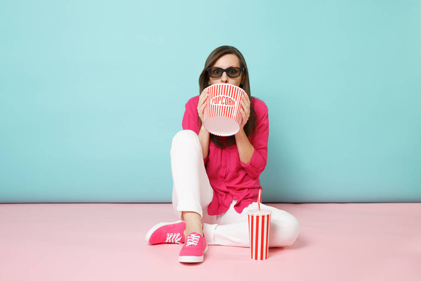 Full length portrait woman in rose shirt, white pants sitting on floor watching movie film isolated on bright pink blue pastel wall background studio. Fashion lifestyle concept. Mock up copy space - 写真・画像