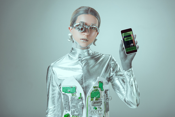 robot holding smartphone with booking application and looking at camera isolated on grey, future technology concept    - Photo, Image