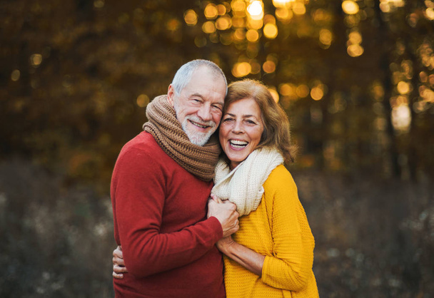 A senior couple standing in an autumn nature at sunset, hugging. - Foto, imagen