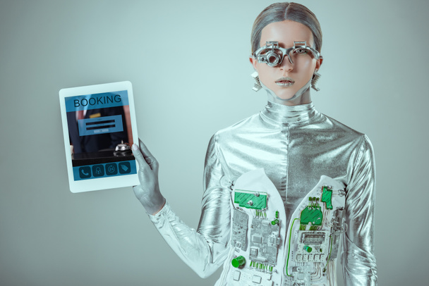 silver robot holding tablet with booking appliance isolated on grey, future technology concept - 写真・画像