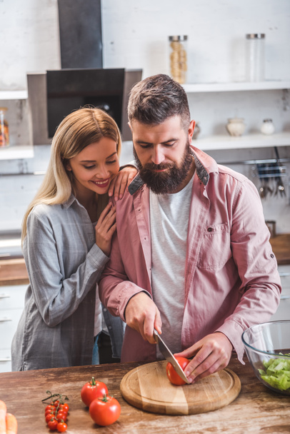 Husband and wife standing in kitchen and preparing salad - Φωτογραφία, εικόνα