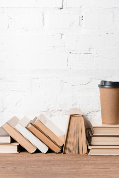 livros e xícara de café descartável na mesa de madeira
 - Foto, Imagem