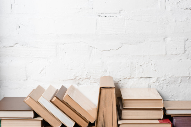 livres avec couvertures rigides près du mur de briques blanches, fond éducatif
 - Photo, image