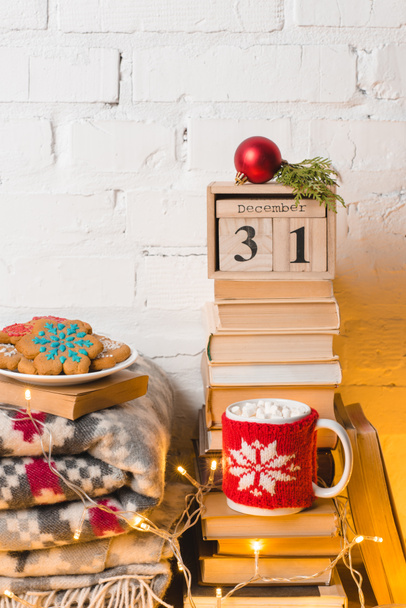 pile of books, blanket, gingerbread cookies, cup of hot chocolate with marshmallows, calendar with 31 december and christmas bauble - Fotoğraf, Görsel