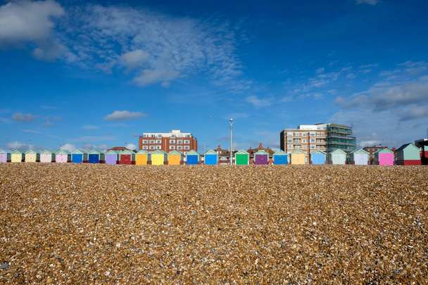Na pierwszym planie jest że kamienistej plaży linii dwadzieścia trzy kolorowe plażowe są w centrum nad nimi jest duże, Błękitne niebo, białe chmury, słońce świeci, Brighton, Sussex, Wielka Kingdon, Uk - Zdjęcie, obraz