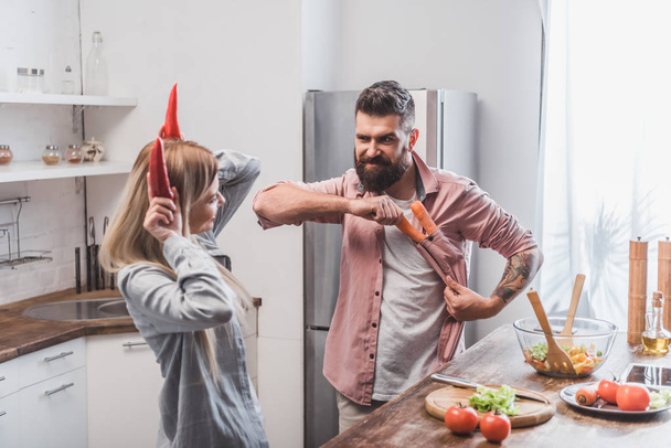 funny couple playing with vegetables at kitchen - Foto, afbeelding